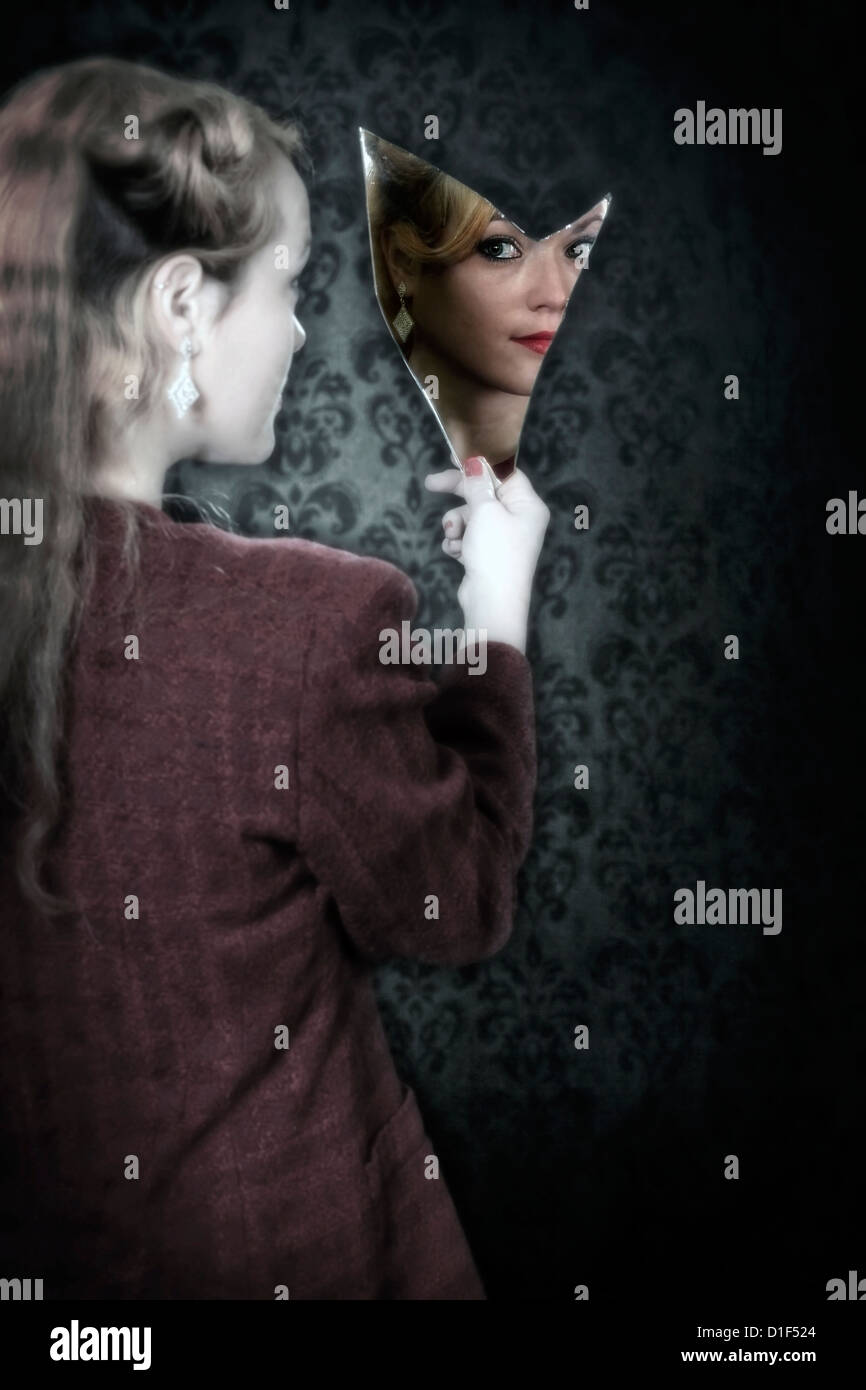 Una donna sta guardando in uno specchio rotto Foto Stock