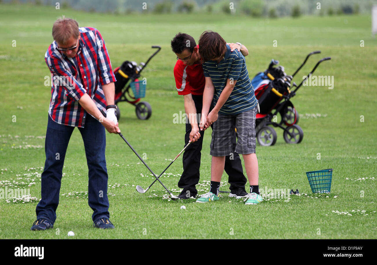 Golf coach David Lang mostra 12-anno-vecchio Max come tee off durante una sessione di pratica presso il golf square Warnemuende in Diedrichshagen, Germania, 28 giugno 2012. Il numero di turisti del golf in Germania è continuamente aumentando. Foto: Jens Buettner Foto Stock