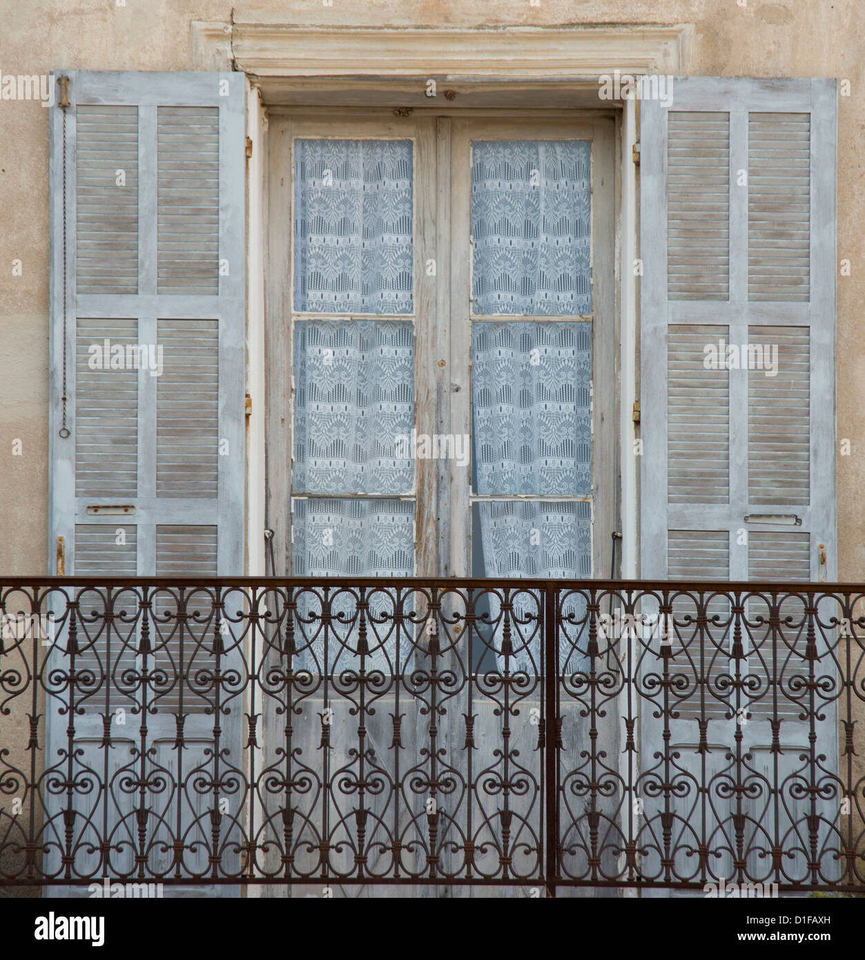 Una vecchia finestra, balcone e le tende nel pittoresco villaggio di Aregno nell entroterra Haute Balagne in Corsica, Francia Foto Stock