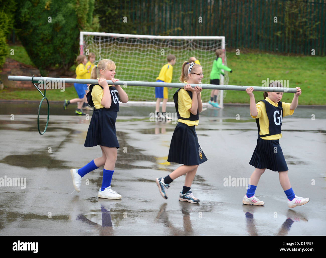 Gli scolari che trasportano un netball obiettivo a Nostra Signora & San Werburgh Cattolico della scuola primaria a Newcastle-under-Lyme, Staffordshi Foto Stock