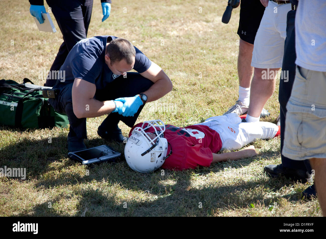 Paramedic parlando di feriti giocatore di calcio con una possibile commozione cerebrale. Altezza di Conway's Park St Paul Minnesota MN USA Foto Stock