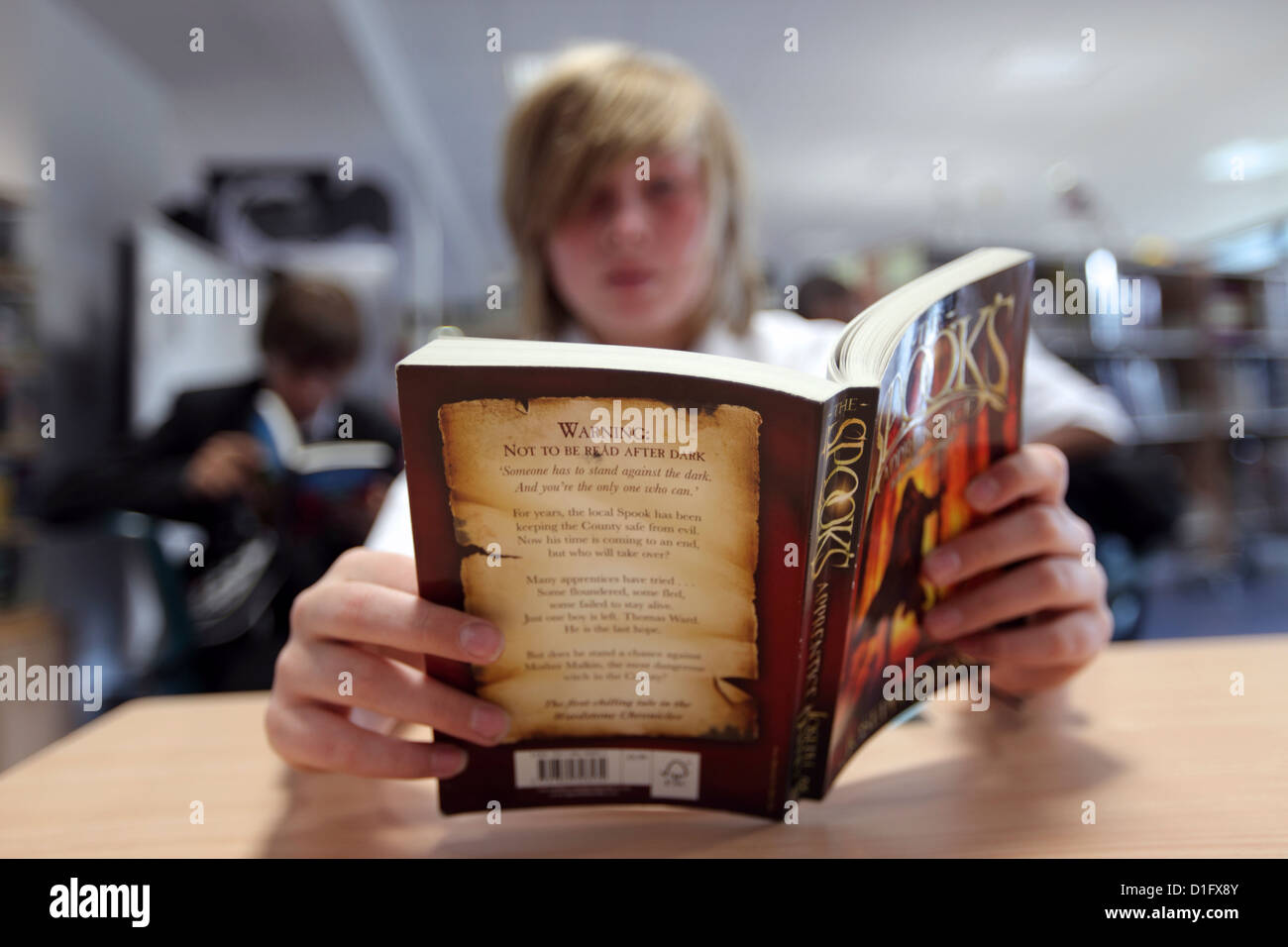 Ragazzo in biblioteca con testa sepolto in un libro. La lettura. Londra, Regno Unito Foto Stock