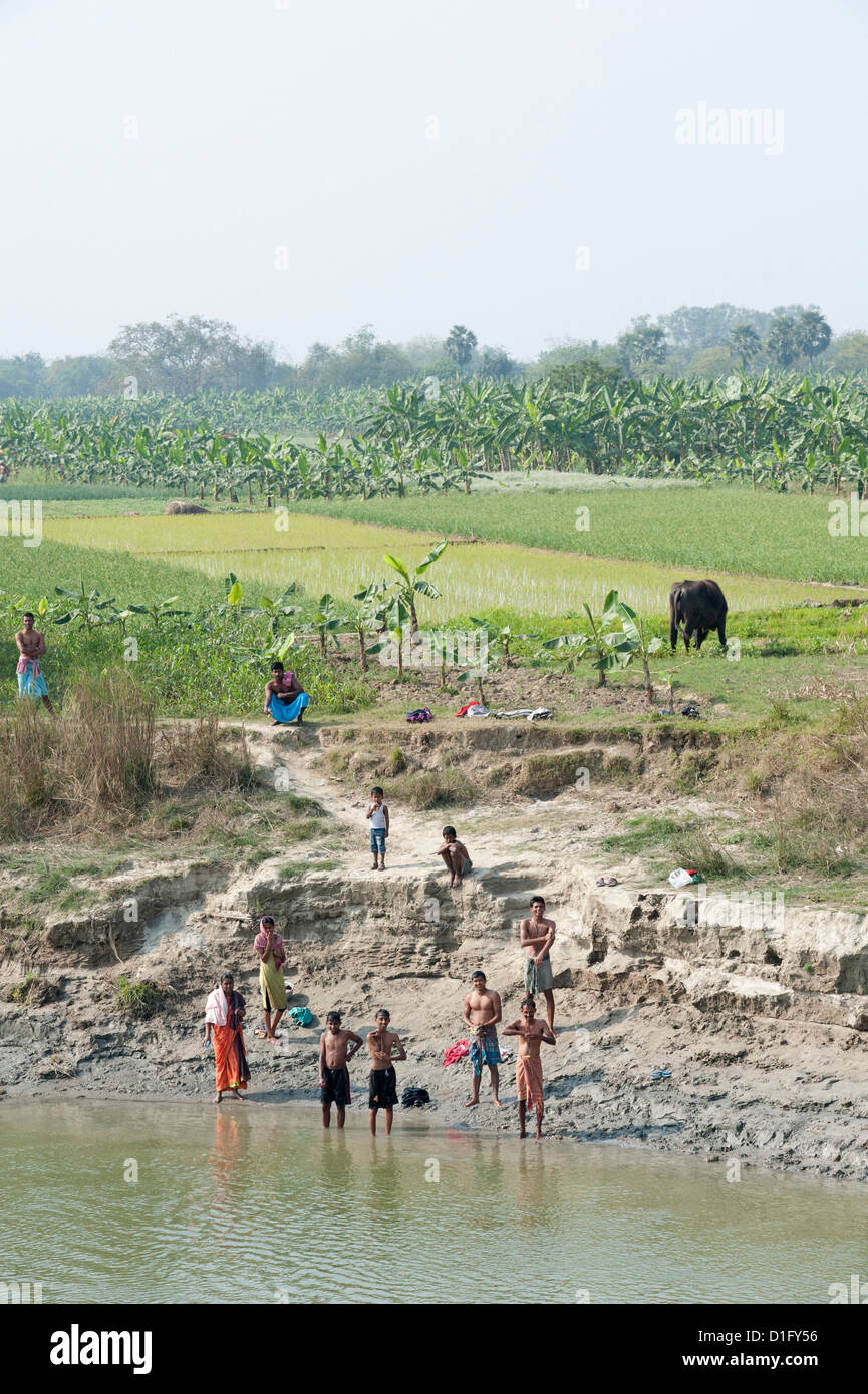 Gli uomini sulle rive del fiume Hugli dopo mattina puja, vicino ricefields e banana risaie, rurale Bengala Occidentale, India Foto Stock