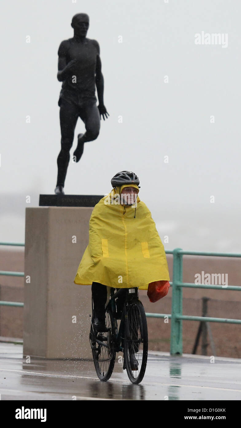 Un ciclista in un giallo brillante cicli poncho lungo Brighton Seafront sotto la pioggia battente. Foto di James Boardman Foto Stock