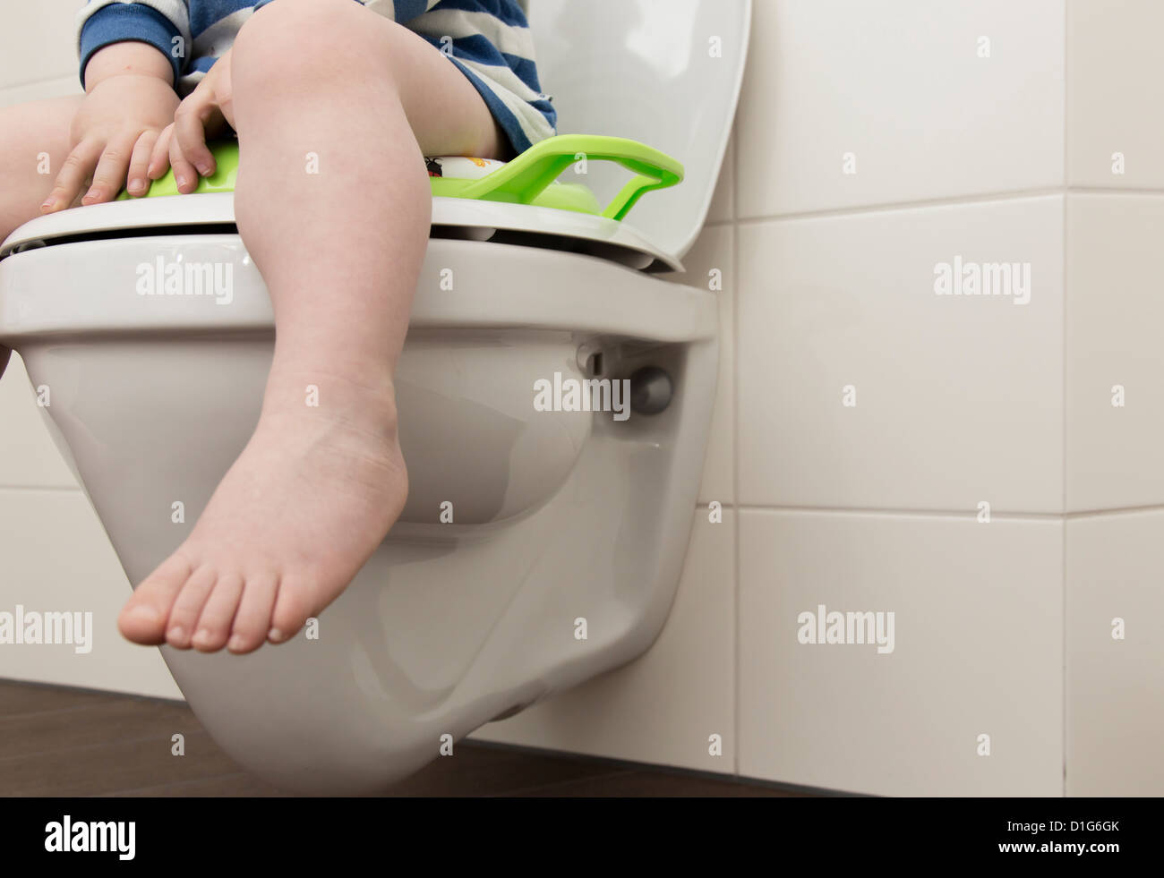 Ragazzo di 2 anni, seduto su un seggiolino su un wc. Foto Stock