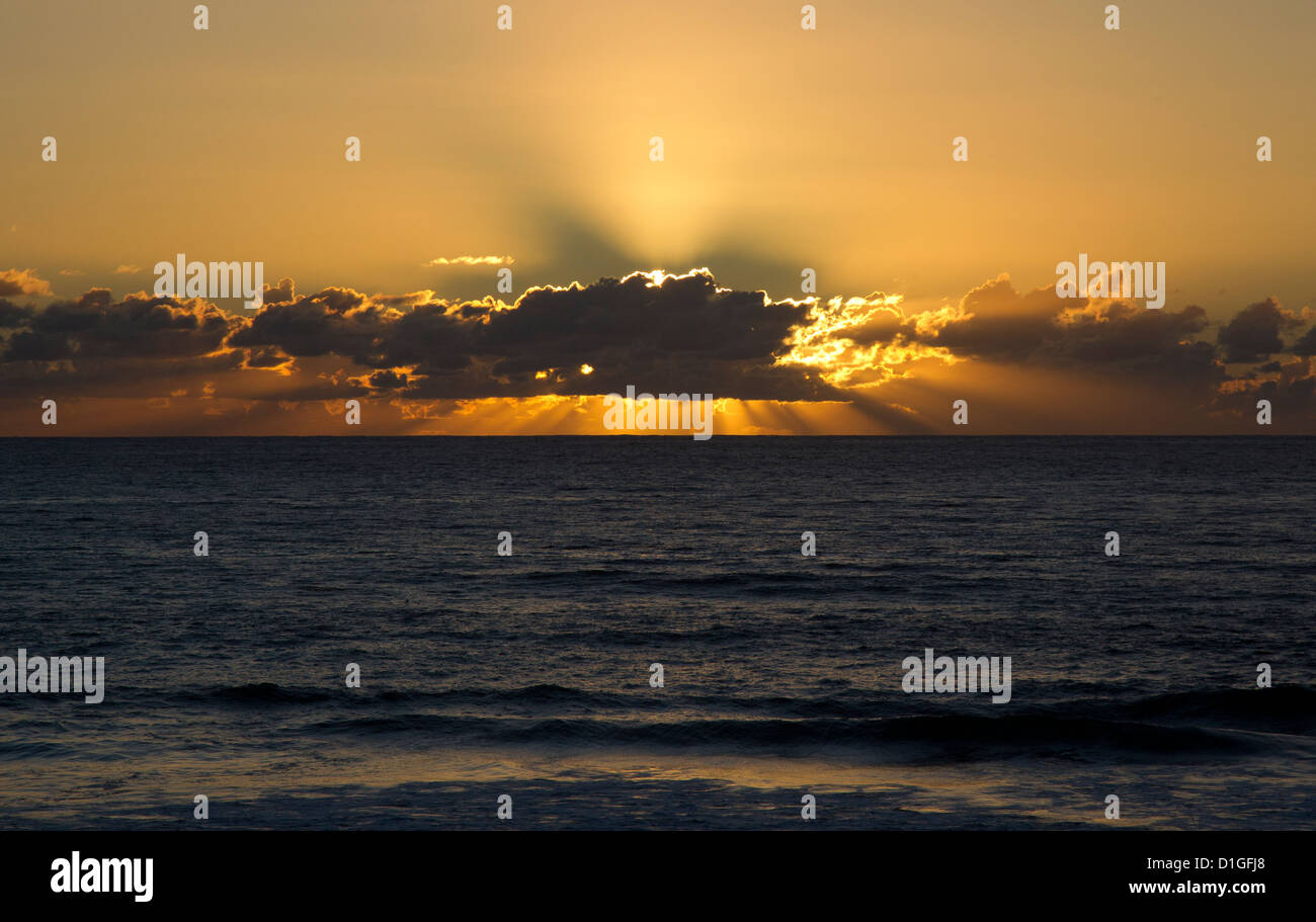 I raggi del sole da dietro nuvole basse Foto Stock