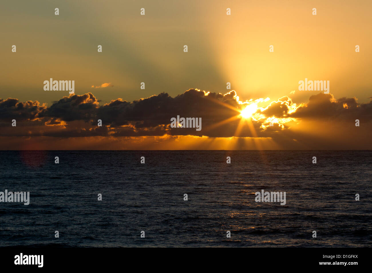 I raggi del sole da dietro nuvole basse Foto Stock