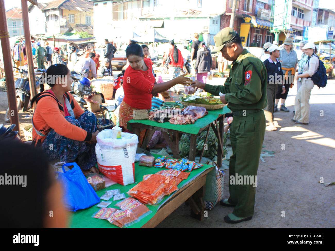 Un membro delle forze militari di produrre gli acquisti da fornitori di mercato sul valore di mercato del giorno nel villaggio di Kalaw, Stato Shan, Myanmar, 31 dicembre 2012. Il picco del Monte Popa ospita il tempio buddista di Taung Tuyin. Foto: Rolf Zimmermann Foto Stock