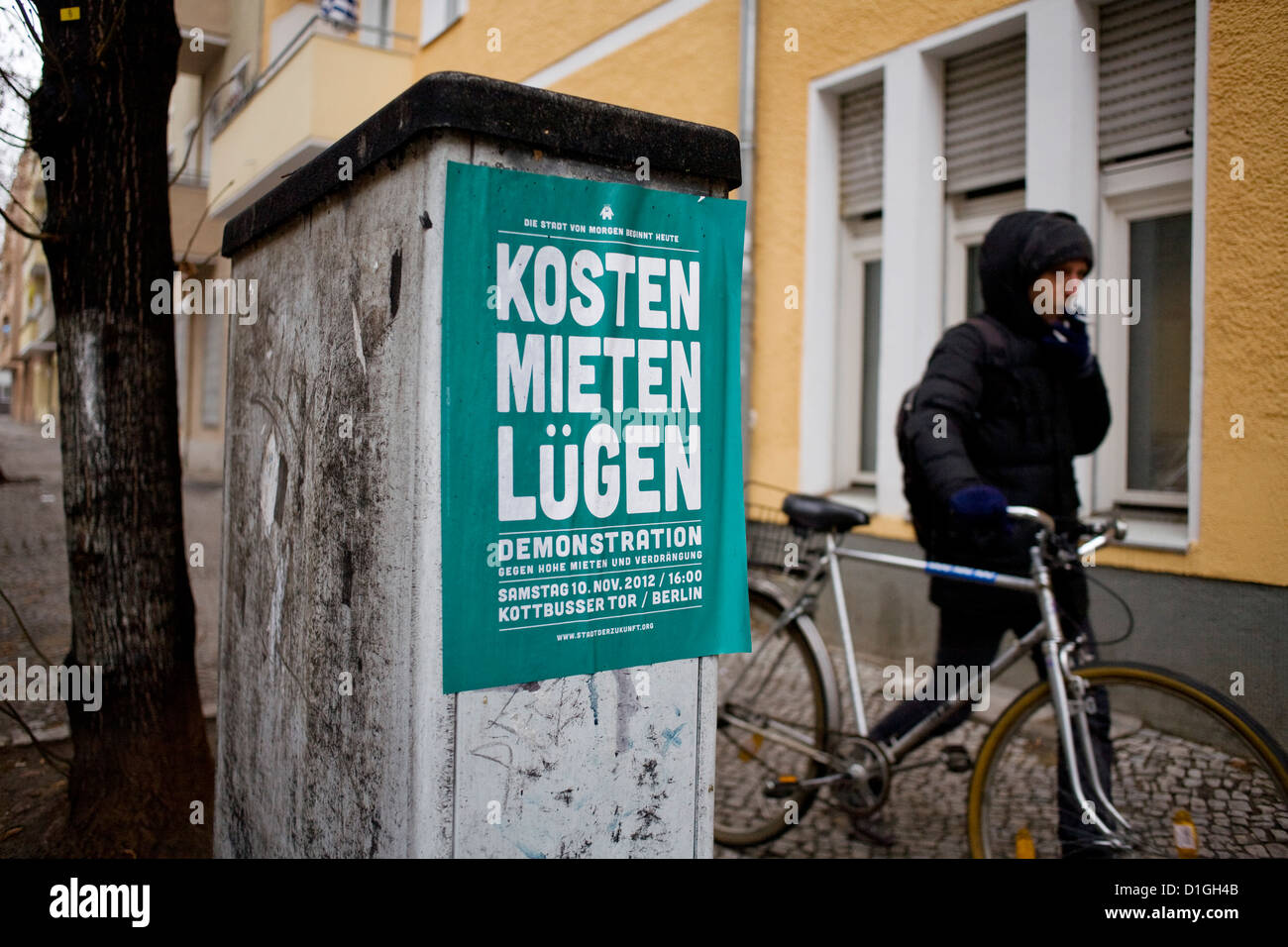 Una persona spingendo una bici e passeggiate fumatori passato un poster la lettura " Costi Affitti sta' è raffigurato in Berlin-Neukoelln, Germania, 19 dicembre 2012. Foto: Inga Kjer Foto Stock