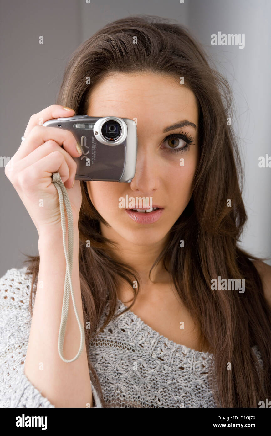 Giovane donna in possesso di una fotocamera compatta di fronte ai suoi occhi. Foto Stock