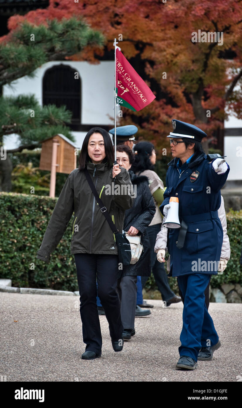 Una guardia di sicurezza dirige il leader di un gruppo turistico che visita Tofuku-ji, Kyoto, Giappone, un luogo famoso e popolare per la visualizzazione del fogliame autunnale (koyo) Foto Stock