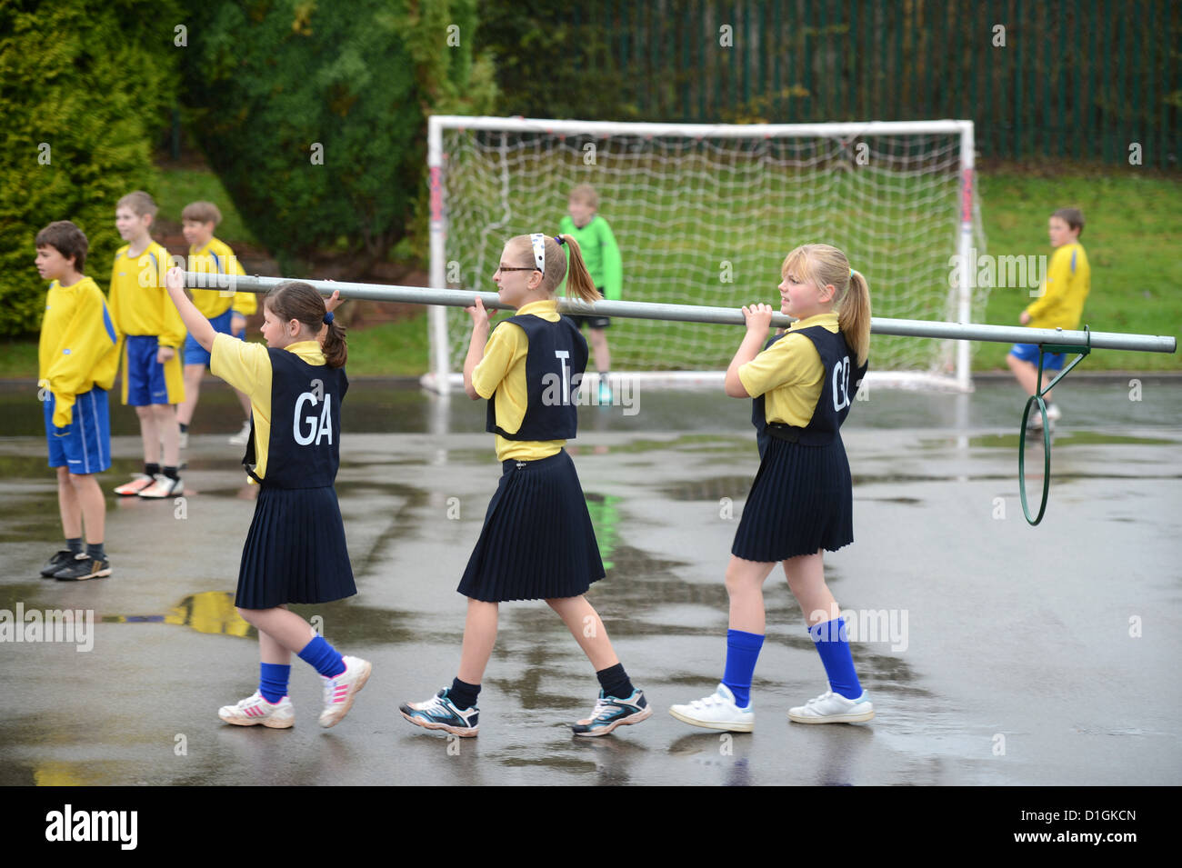 Gli scolari che trasportano un netball obiettivo a Nostra Signora & San Werburgh Cattolico della scuola primaria a Newcastle-under-Lyme, Staffordshi Foto Stock