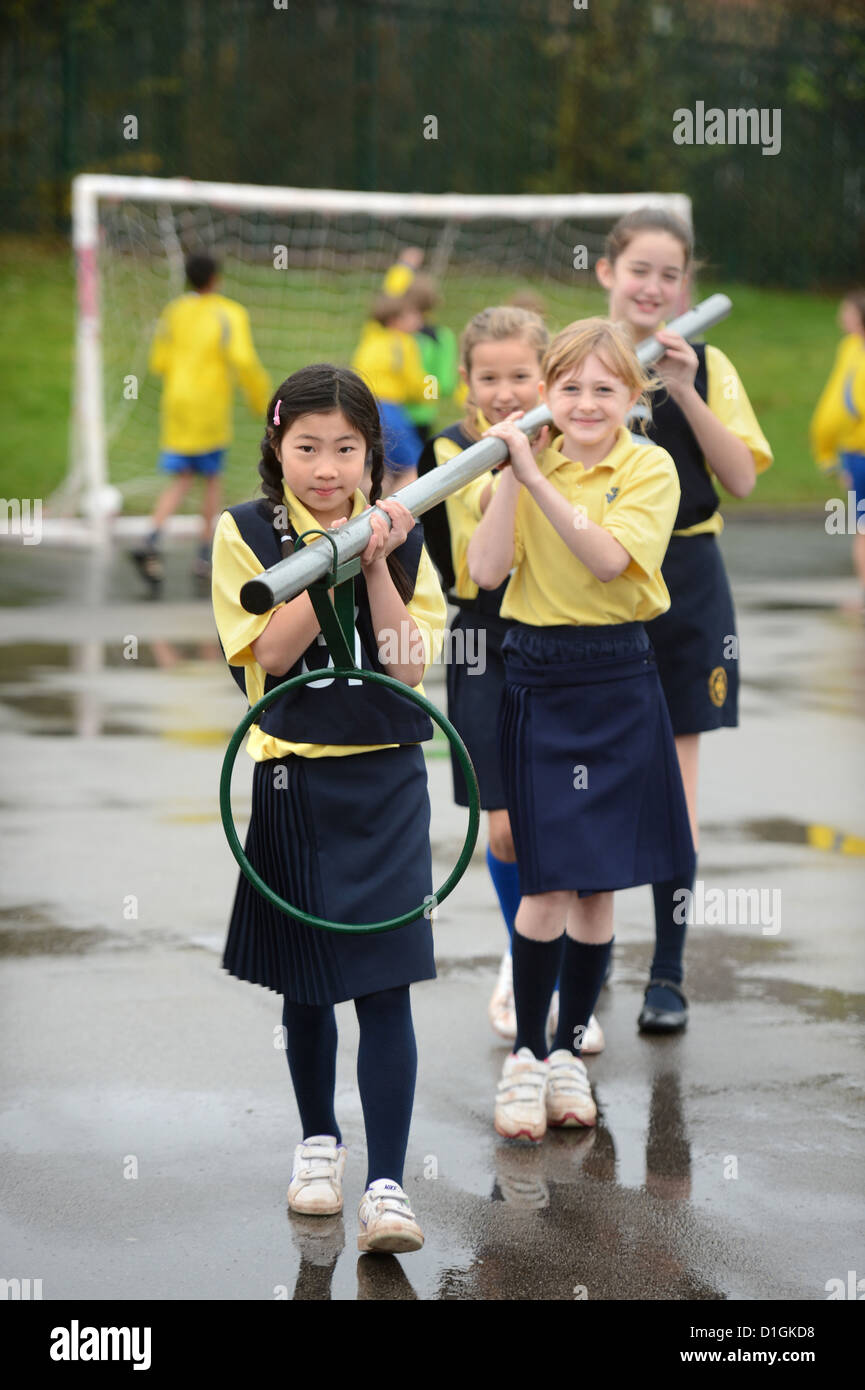 Gli scolari che trasportano un netball obiettivo a Nostra Signora & San Werburgh Cattolico della scuola primaria a Newcastle-under-Lyme, Staffordshi Foto Stock