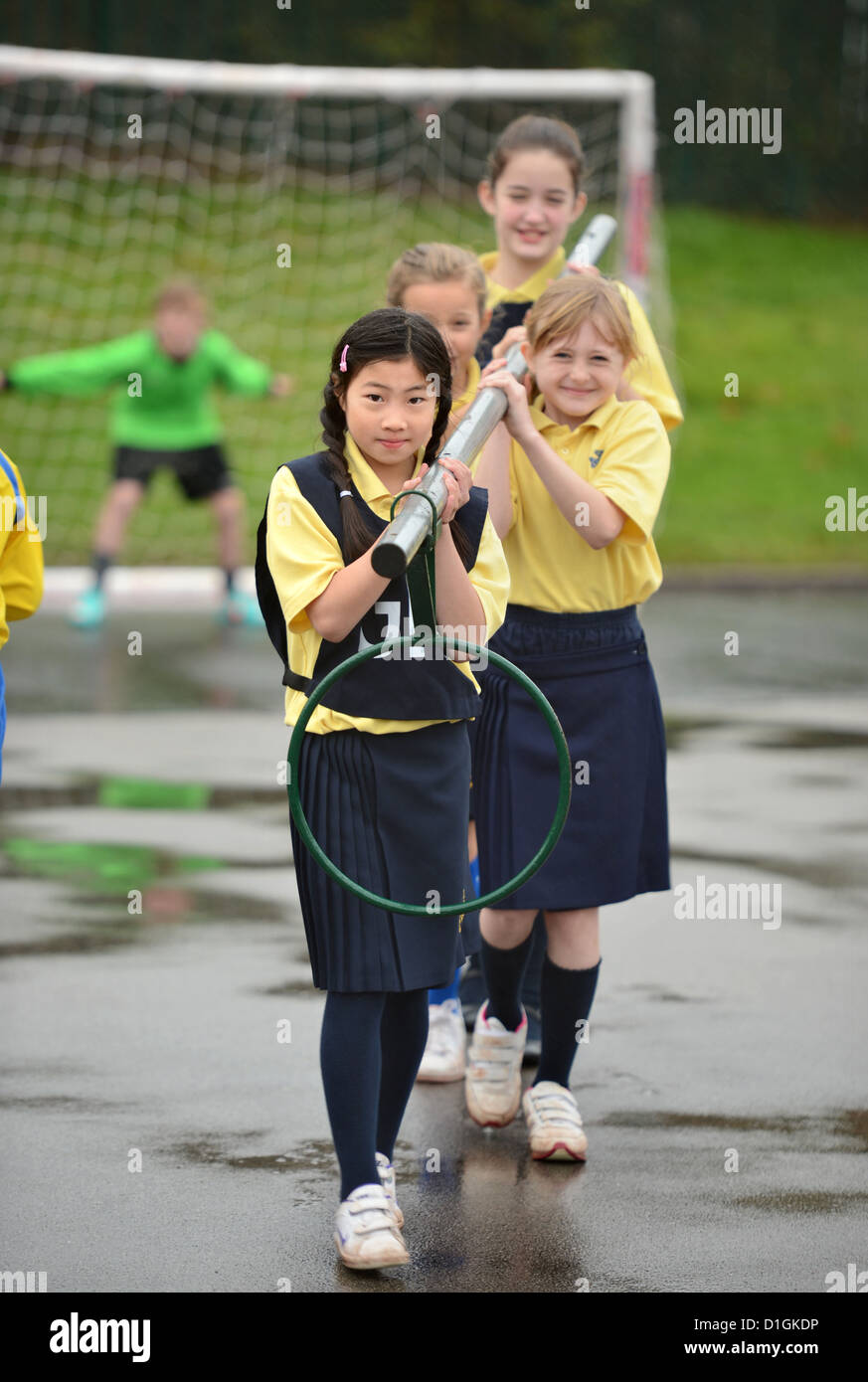 Gli scolari che trasportano un netball obiettivo a Nostra Signora & San Werburgh Cattolico della scuola primaria a Newcastle-under-Lyme, Staffordshi Foto Stock