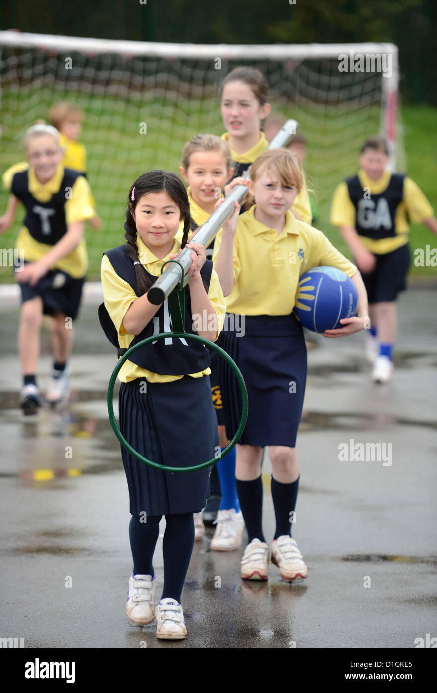 Gli scolari che trasportano un netball obiettivo a Nostra Signora & San Werburgh Cattolico della scuola primaria a Newcastle-under-Lyme, Staffordshi Foto Stock