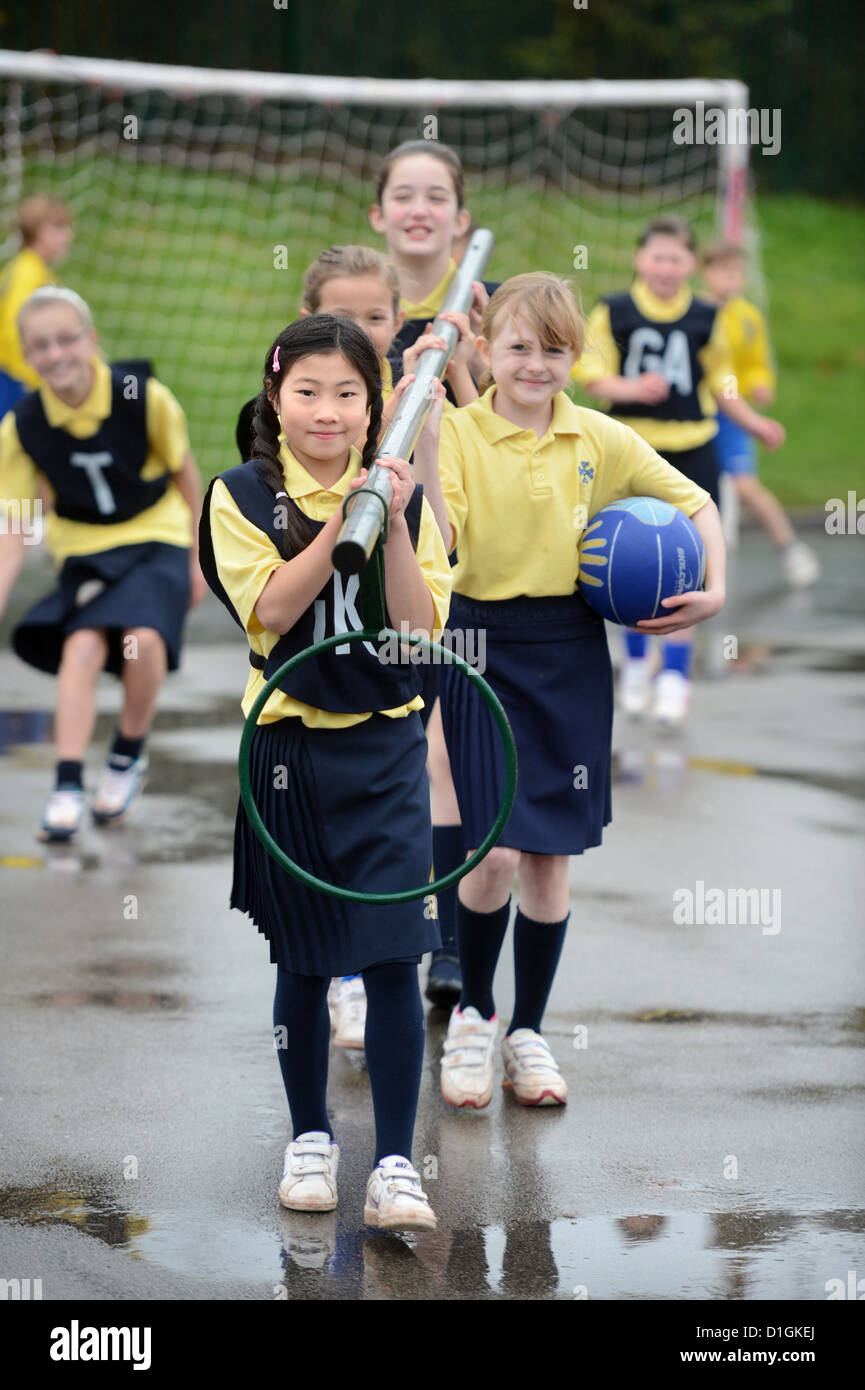 Gli scolari che trasportano un netball obiettivo a Nostra Signora & San Werburgh Cattolico della scuola primaria a Newcastle-under-Lyme, Staffordshi Foto Stock