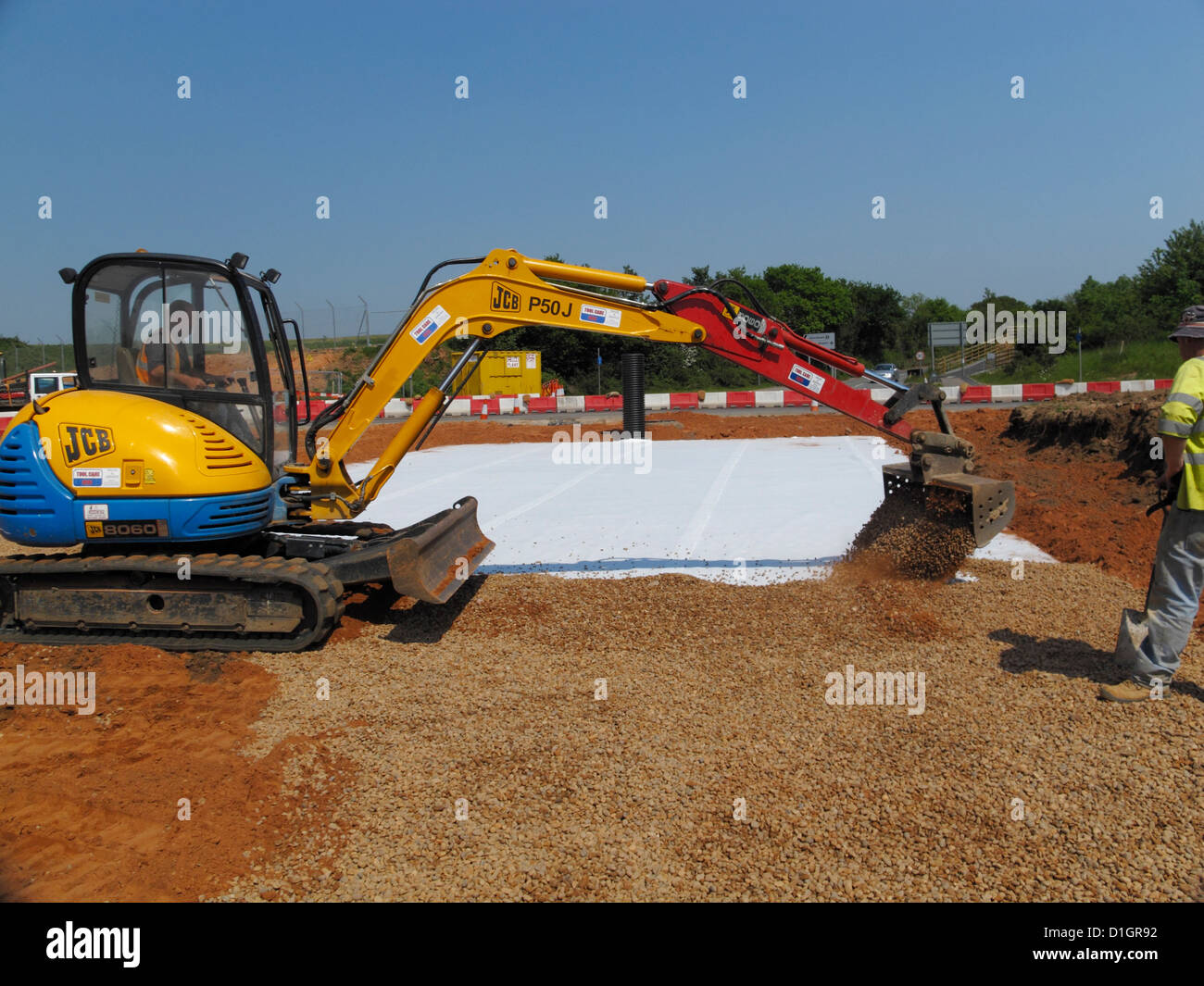 JCB riempimento oltre il drenaggio sostenibili stormbloc cassa plastica attenuazione sistema del serbatoio sul Regno Unito nuova strada sito in costruzione Foto Stock