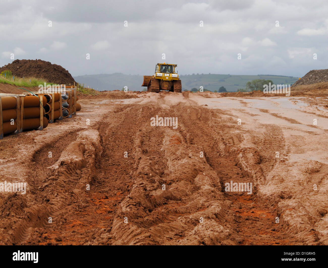 I cingoli dei bulldozer in gloopy spessa fango umido sul sito di sterro per la costruzione di una nuova strada regno unito Foto Stock