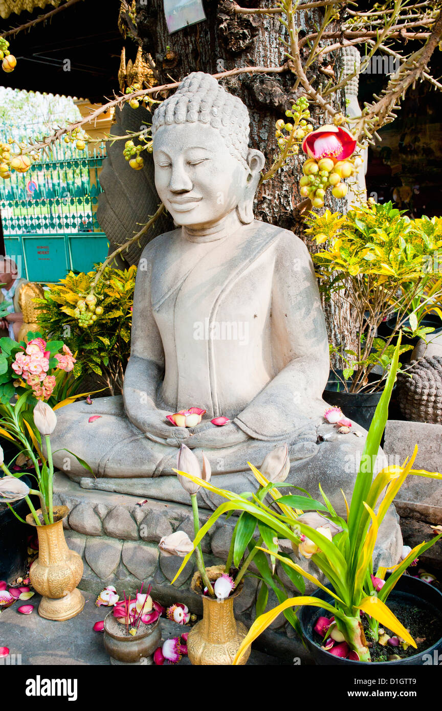 Stone statua del Buddha coperto di fiori presso il Palazzo Reale di Phnom Penh, Cambogia, Indocina, Asia sud-orientale, Asia Foto Stock