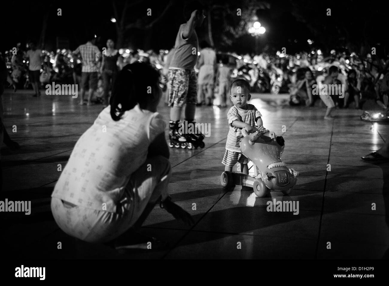 Un giovane bambino guardando a sua madre ad Hanoi, Vietnam Foto Stock