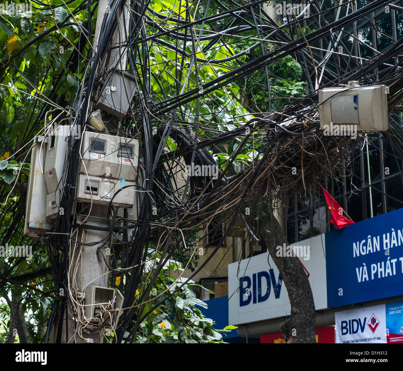 Accozzaglia di fili in pole nel quartiere vecchio di Hanoi, Vietnam Foto Stock