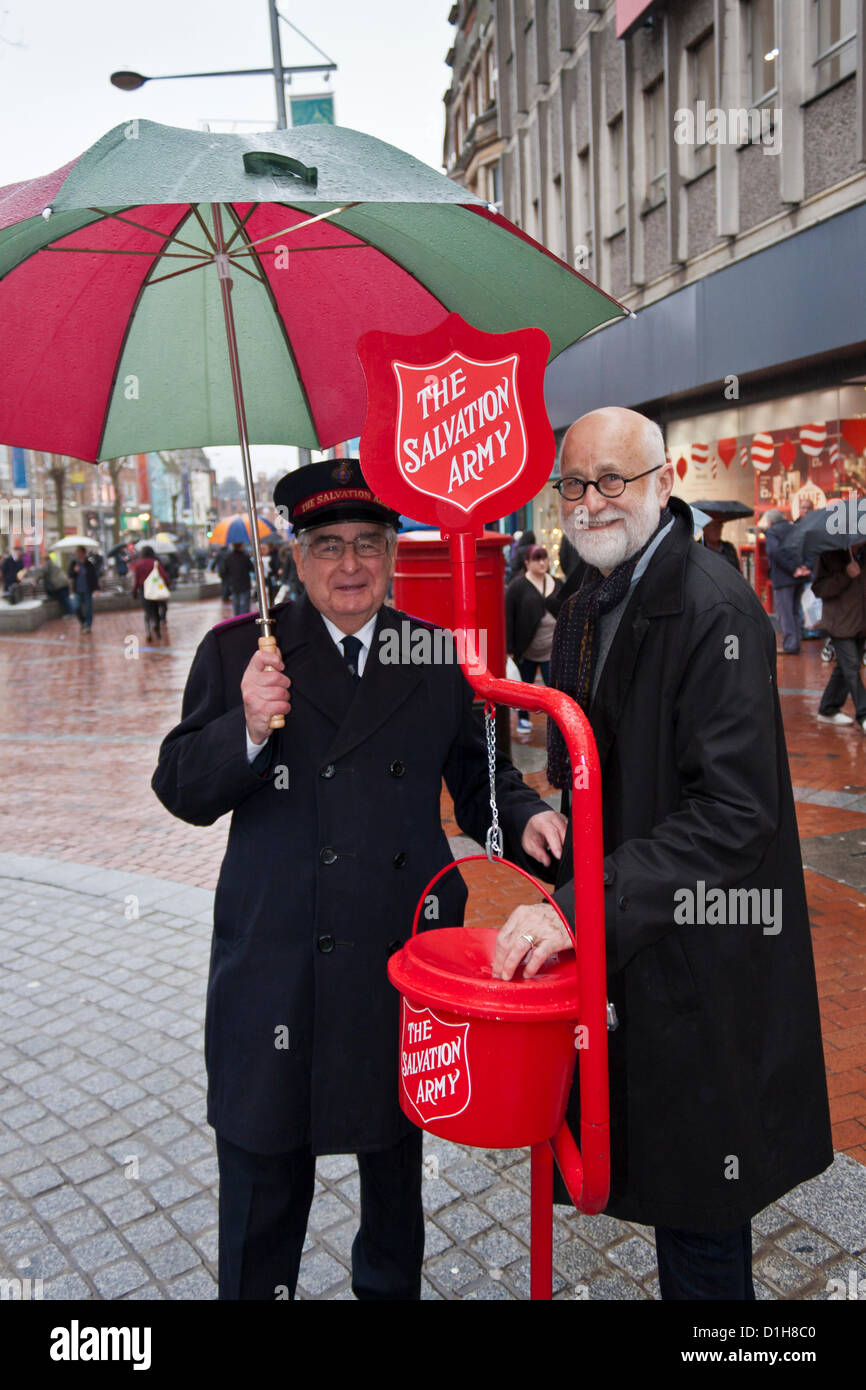 Il 22 dicembre 2012, Reading, Regno Unito. Il sig. Michael Bennett di lettura di Esercito della Salvezza (sinistra) raccoglie fondi in centro città per l'organizzazione religiosa a Natale: un membro del pubblico fa una donazione. L'Esercito della salvezza è una denominazione cristiana e movimento internazionale noto per la sua opera di carità in tutto il mondo. © Danny Callcut Foto Stock