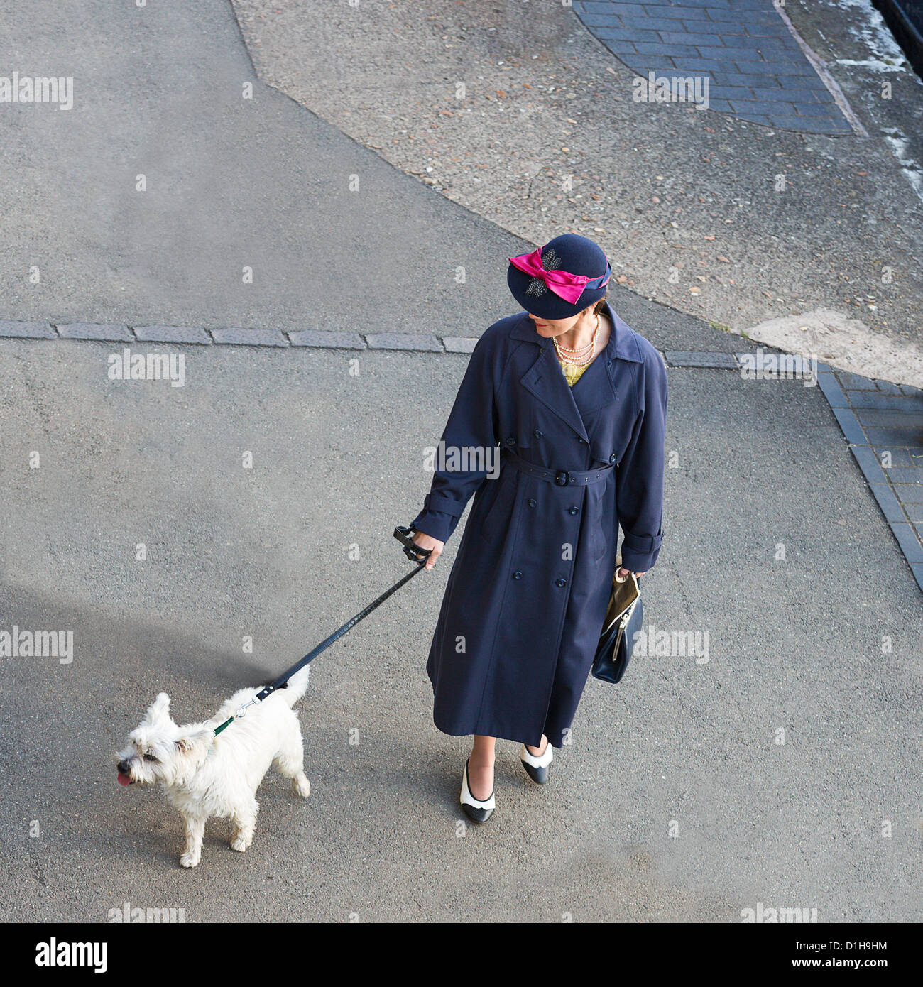 Ricreato 1940's Fashion Style - lady in belted trench coat, due pompe di tono (scarpe) perle & hat con nastro di prua e cane sul filo Foto Stock