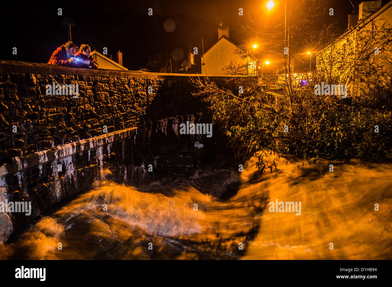 Sabato 22 dicembre 2012. West Calder, vicino a Aberystwyth, Galles Ceredigion REGNO UNITO dopo una giornata di prolungato heavy rain, il fiume Leri si è nuovamente aumentata a livelli che sono causa di ansia in questo villaggio, che ha subito danni devastanti a causa delle inondazioni del 7/8 giugno 2012. L'autorità locale provvisto dei sacchi di sabbia per i residenti locali per proteggere le loro proprietà, e l'Agenzia per l'ambiente era la previsione che i livelli del fiume si sarebbe presto iniziare a scendere una volta che la pioggia era cessata . MICK FOTHERGILL (e figlio BEN) guarda ansiosamente come il fiume scorre oltre la sua casa che è stata duramente colpita dalle inondazioni in precedenza. Foto Stock