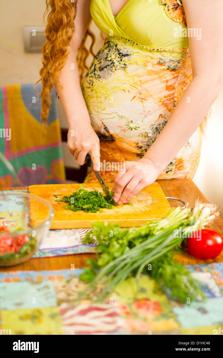 Donna incinta s le mani e il ventre taglio sulla cucina con il cibo sano il concetto di cibo e di uno stile di vita sano Foto Stock