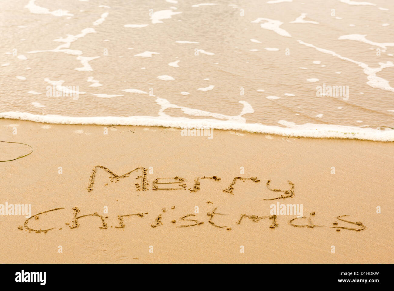 Buon Natale scritta nella sabbia sulla spiaggia Foto Stock