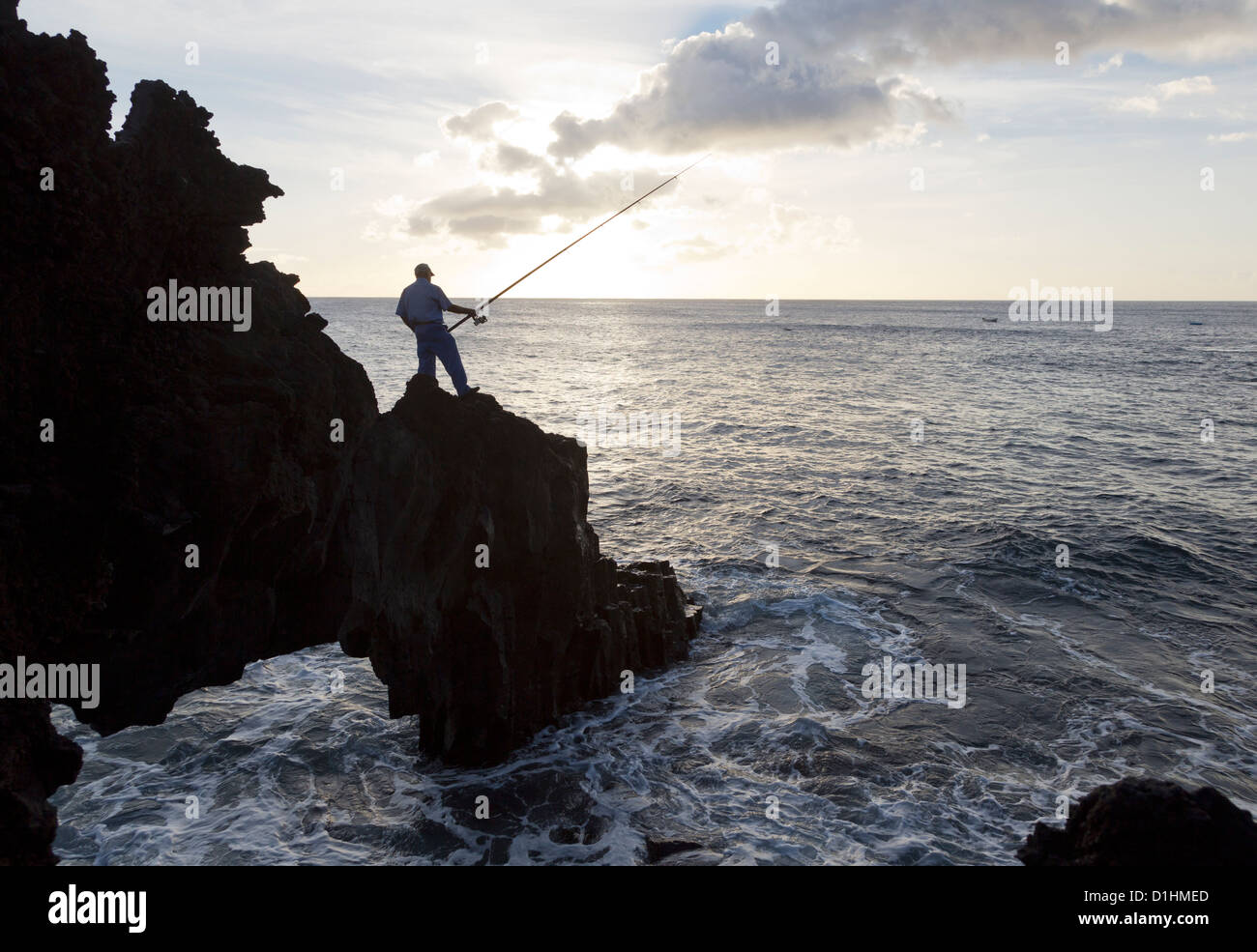 Il pescatore su una costa di roccia Foto Stock