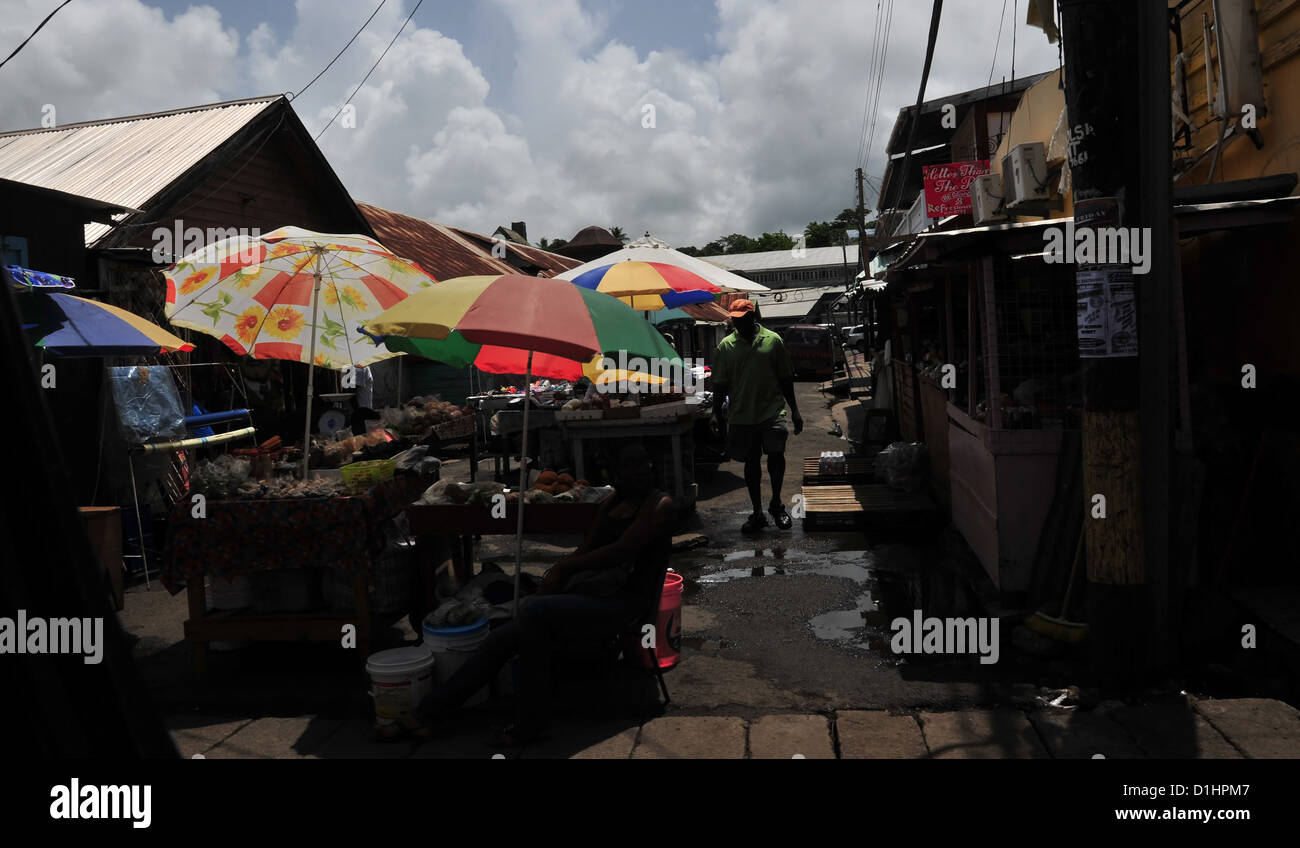 African-West Indian man walking passato ombrelloni colorati sfumature al mercato del sabato bancarelle Grenville, Grenada, West Indies Foto Stock