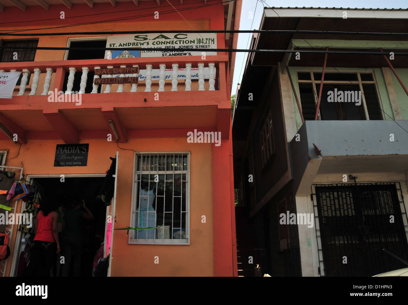 Vista stradale African-West Indian ragazza entra in vernice arancione Nadia Boutique, Ben Jones Street, Grenville, Grenada, West Indies Foto Stock