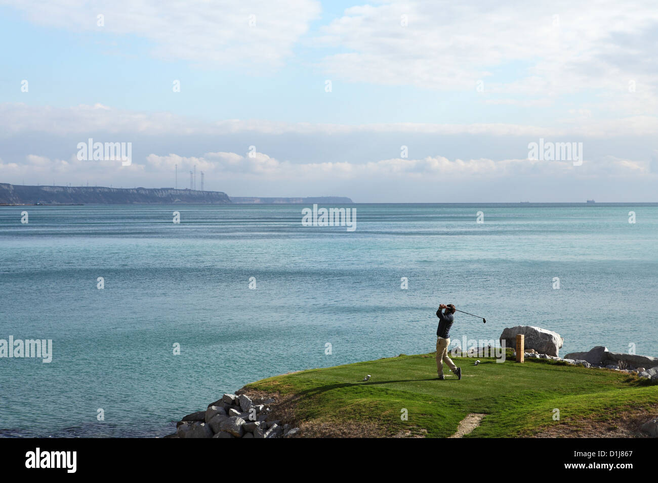 Un giocatore di golf tees off oltre un pericolo in acqua al Thracian Cliffs Golf Course a Varna, Bulgaria. Foto Stock