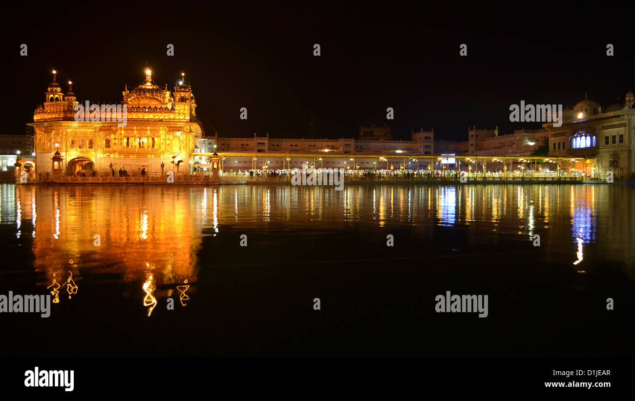 Darbar Sahib, conosciuto anche come Tempio d'oro incandescente nella notte con il suo riflesso nella piscina sacra. Darbar Sahib è più sacra icona per i sikh. Foto Stock