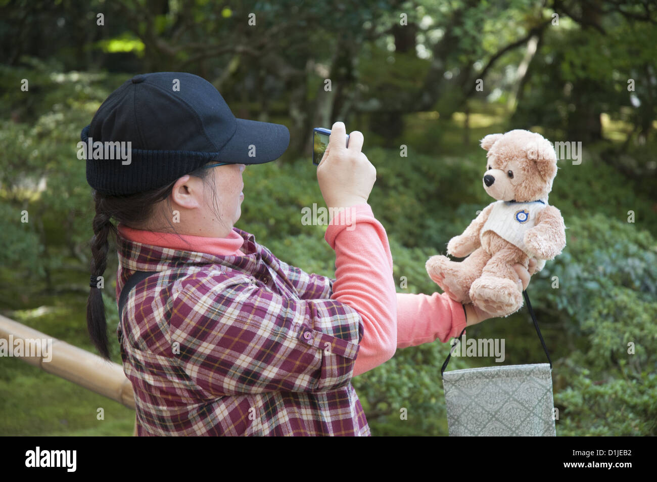 Giovane donna giapponese a fotografare il suo orsacchiotto di peluche su una visita al Tempio Ginkakuji in Kyoto Foto Stock