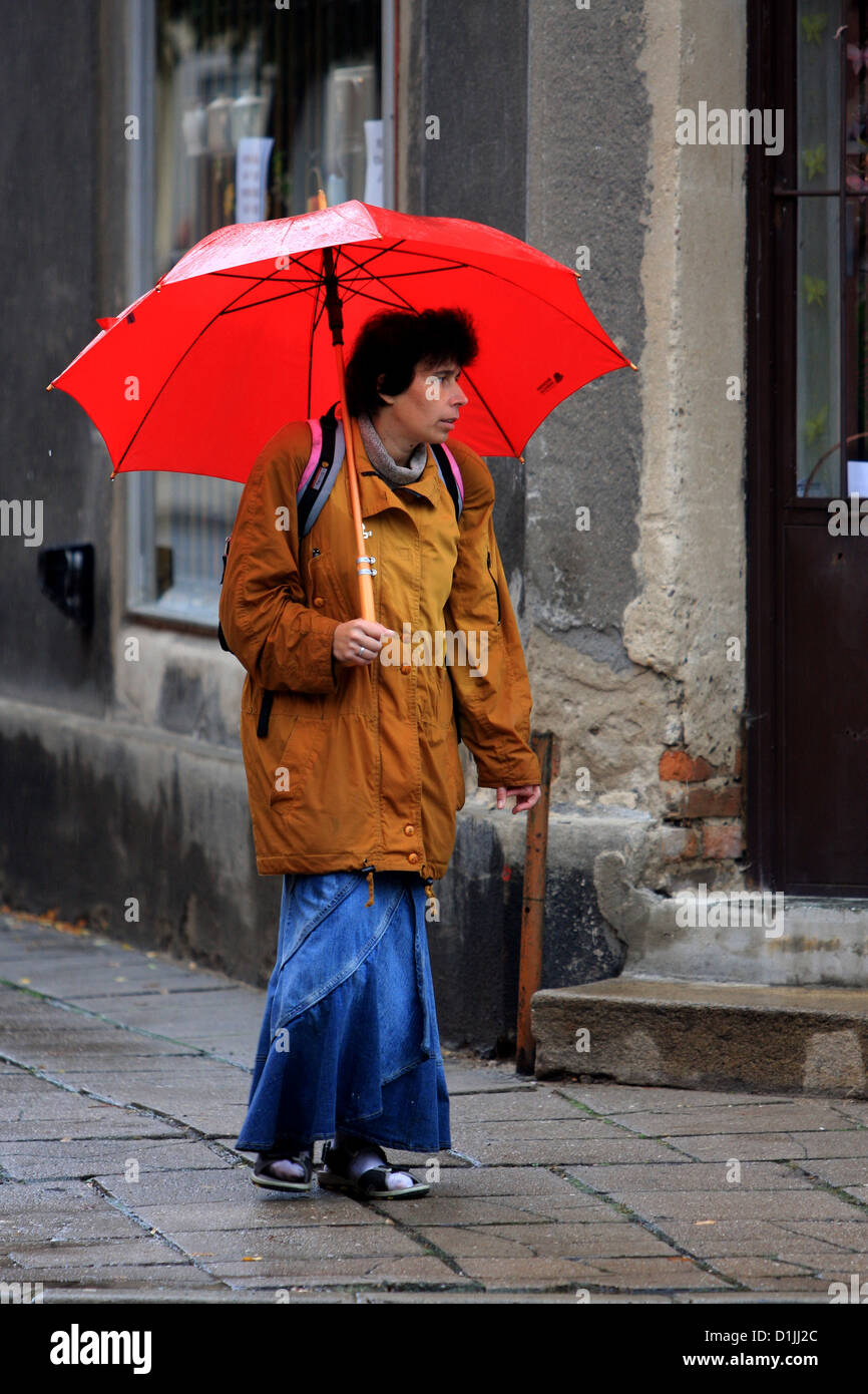 Donna in strada vuota con un ombrello rosso Foto Stock