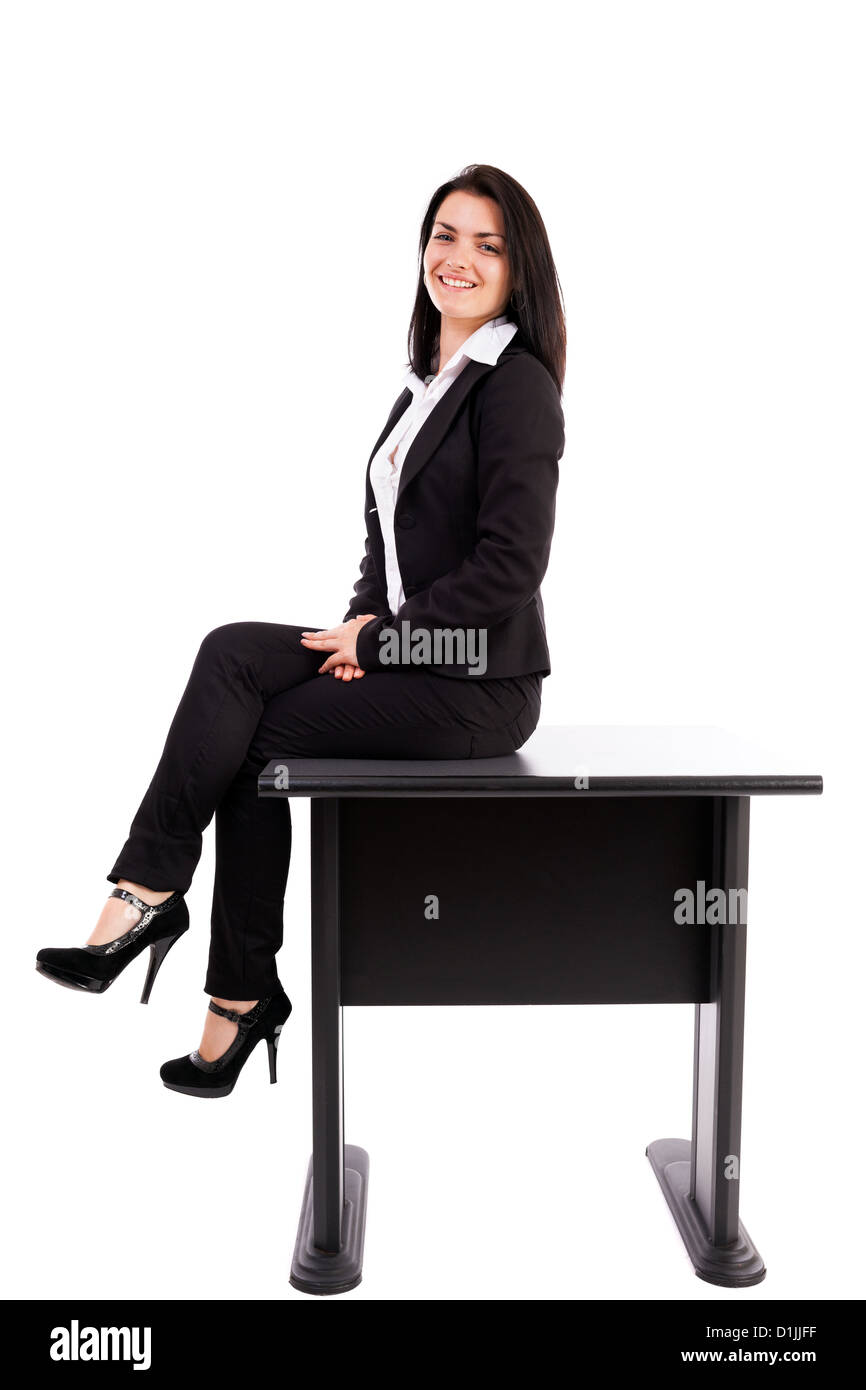 A piena lunghezza Ritratto di una giovane imprenditrice seduta sul tavolo isolato su sfondo bianco Foto Stock