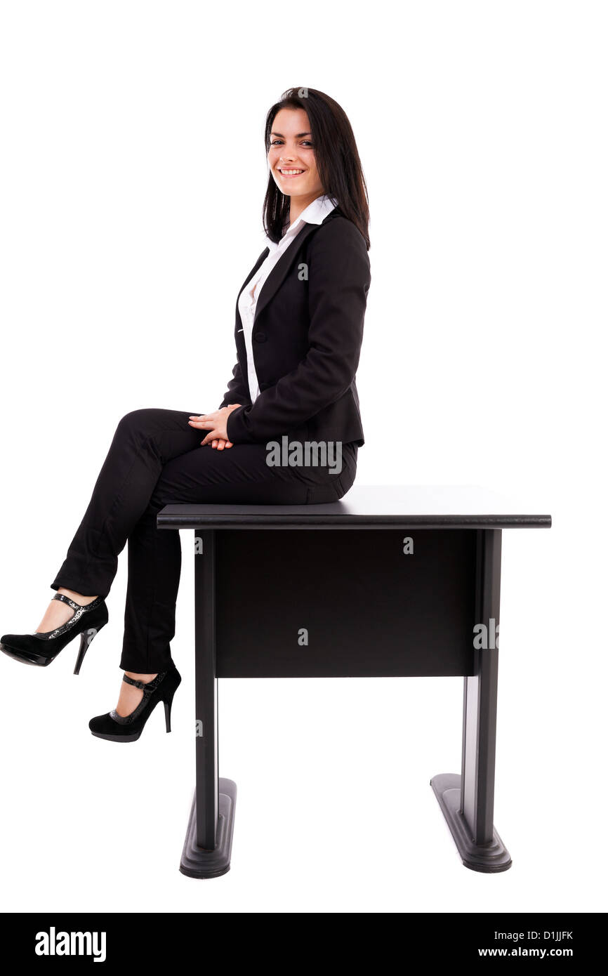 A piena lunghezza Ritratto di una giovane imprenditrice seduta sul tavolo isolato su sfondo bianco Foto Stock