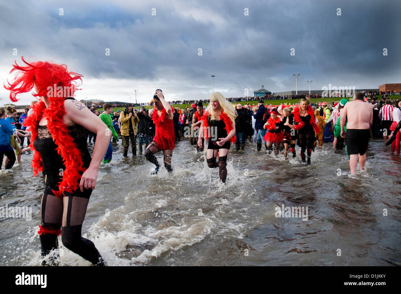 Uomini vestiti come caberet ragazze prendere parte all'annuale Boxing Day Dip in Seaburn, Sunderland, UK organizzato dal Sunderland Lions Club. Il 26 dicembre 2012. Foto Stock