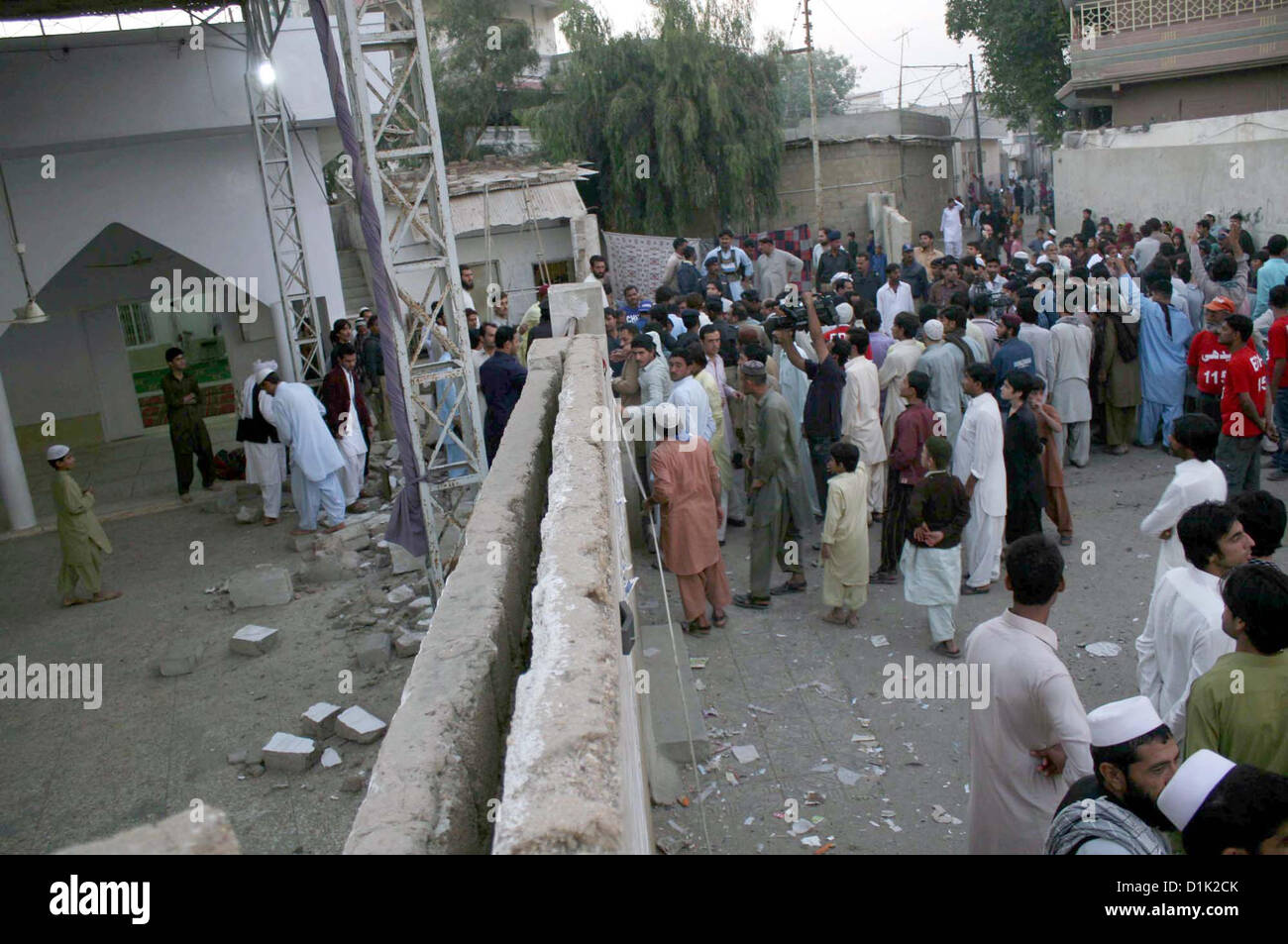 Le persone si radunano presso il sito e il relitto del motociclo distrutto visto dopo un attentato vicino a Jama Masjid Haji Khan si trova in Jannat Gul cittadina nei pressi di Piazza Al-Asif a Sohrab Goth area in Karachi Mercoledì, Dicembre 26, 2012. Almeno cinque persone sono state ferite quando una bomba apparentemente montato in una motocicletta è esplosa al di fuori di una moschea in Sohrab Goth. Foto Stock