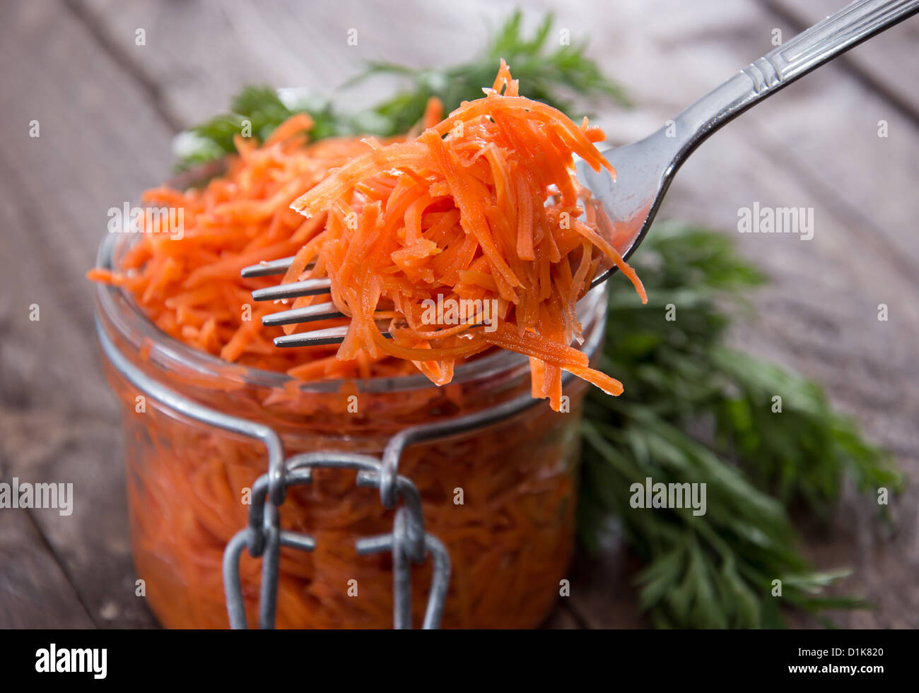 Forcella con Insalata di carote davanti a un bicchiere Foto Stock