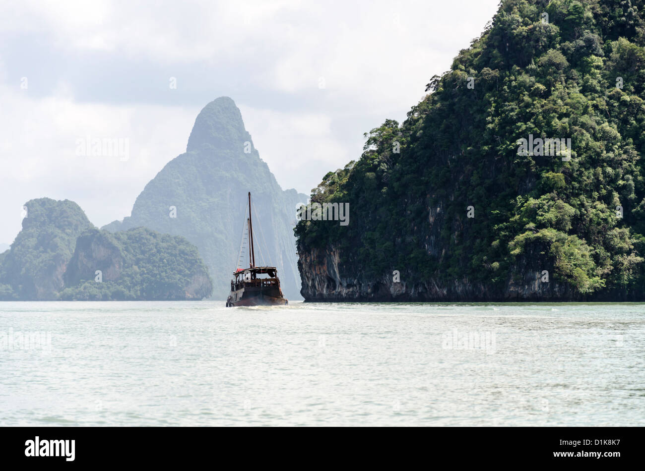 In legno barca turistica andando da isole con scogliere calcaree in Ao Phang-Nga Parco Nazionale Marino nel sud della Thailandia Foto Stock