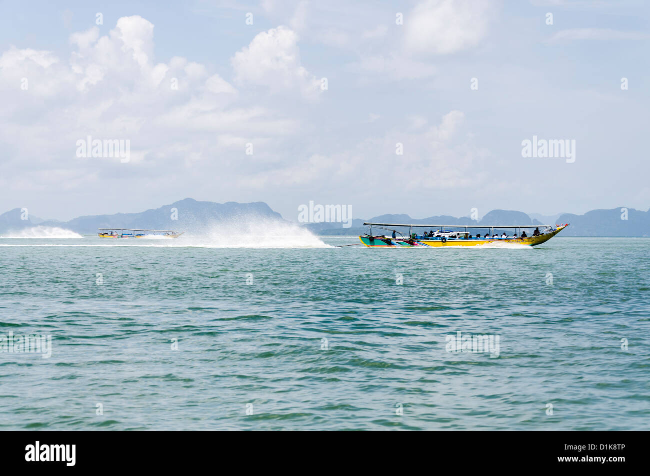 Accelerando longtail barche di spruzzare acqua dietro di loro in Ao Phang-Nga Parco Nazionale Marino nel sud della Thailandia Foto Stock