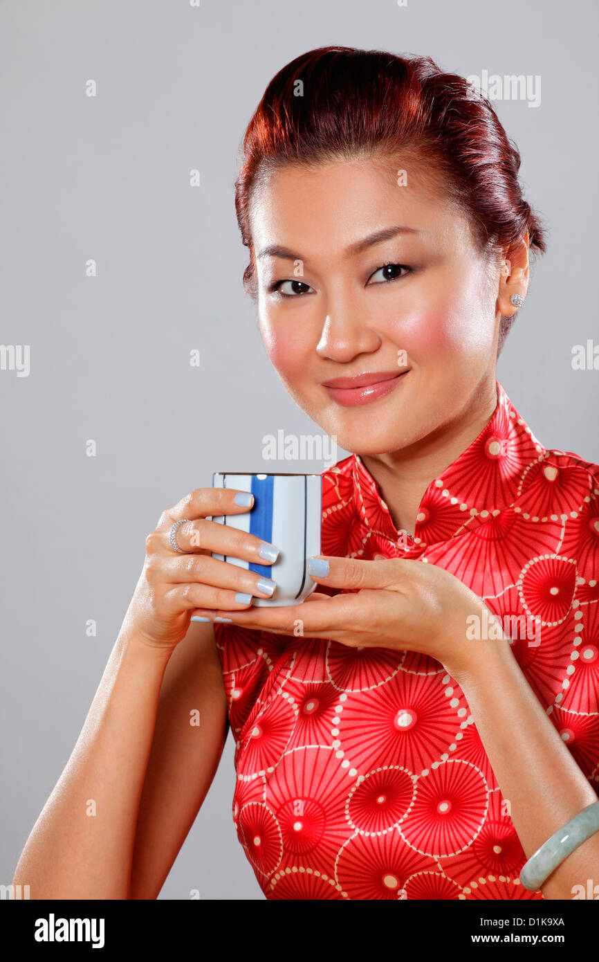 Ritratto di donna che indossa Cheongsam e azienda tazza da tè Foto Stock