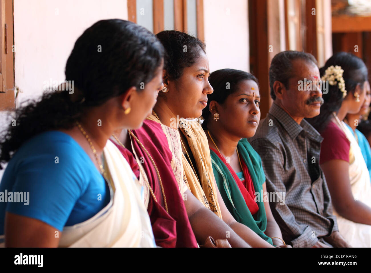 Un gruppo di persone sedute al di fuori della casa a una funzione in Kerala. Foto Stock