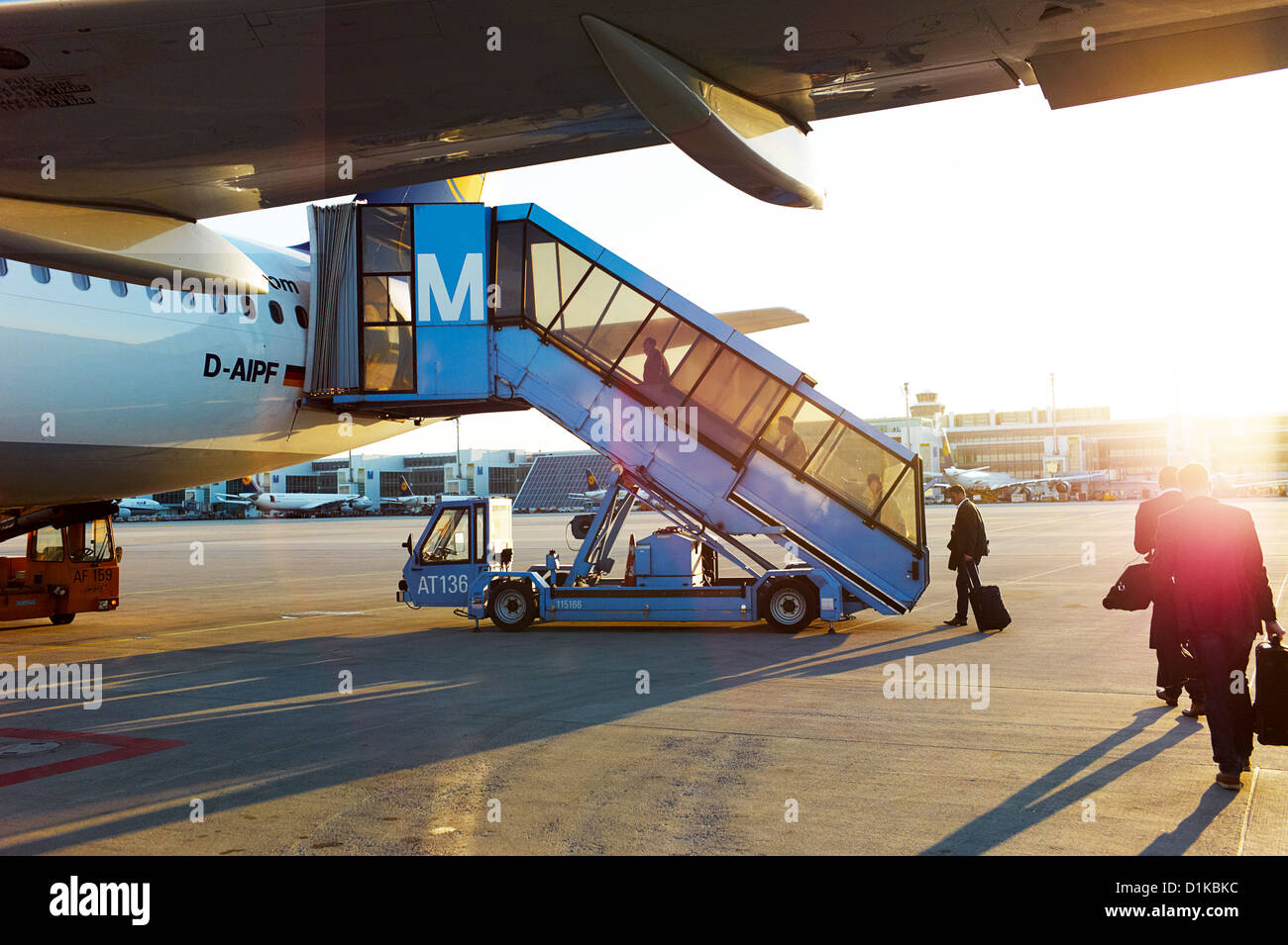 Uomini d'affari e per i viaggiatori a bordo di un aereo su asfalto al tramonto Foto Stock