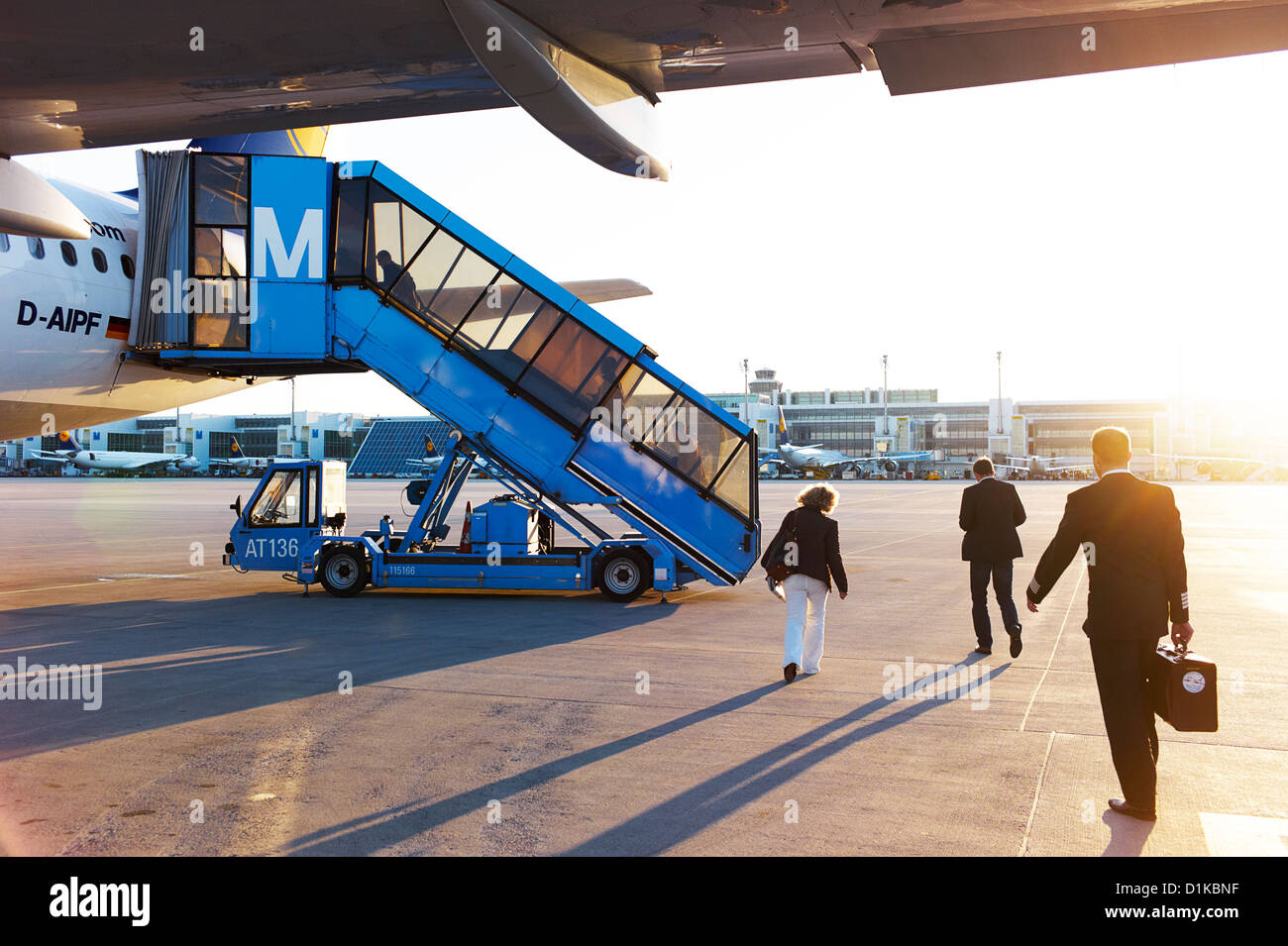 Uomini d'affari e per i viaggiatori a bordo di un aereo su asfalto al tramonto Foto Stock