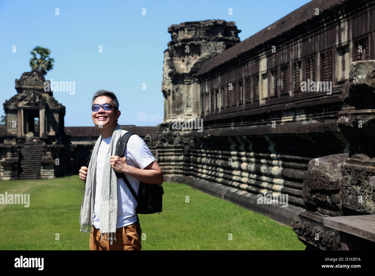 Turistico con uno zaino in piedi di fronte a un muro di Angkor Wat, Cambogia Foto Stock
