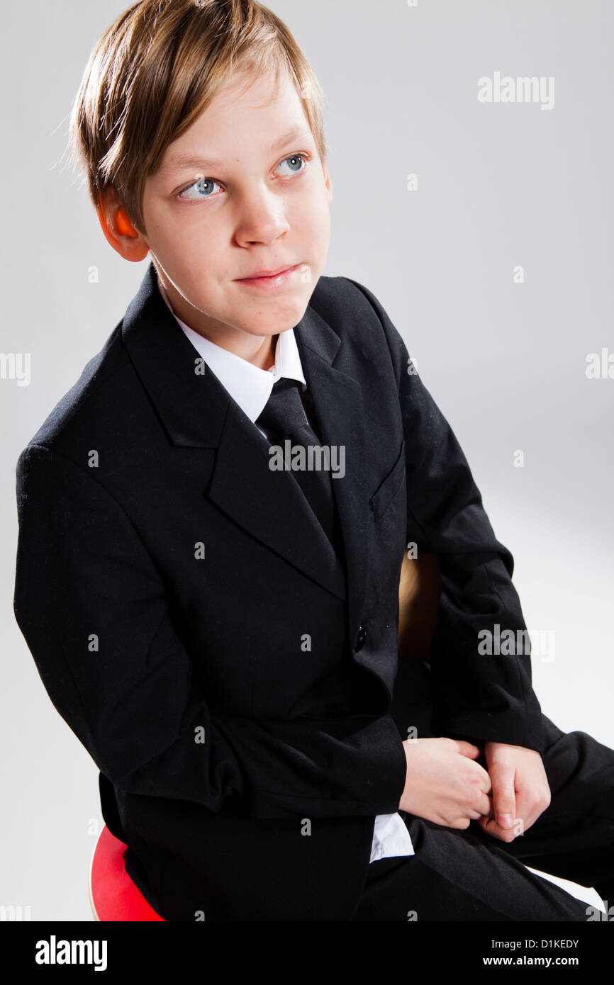 Ritratto in studio di sorridenti giovane ragazzo indossa abito nero Foto Stock